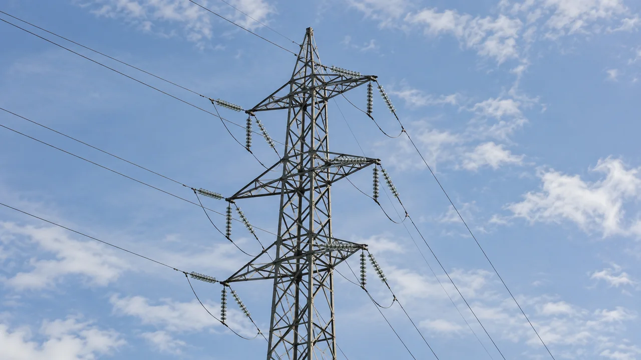 Pylône haute tension en acier et câbles du réseau électrique vus depuis le sol.